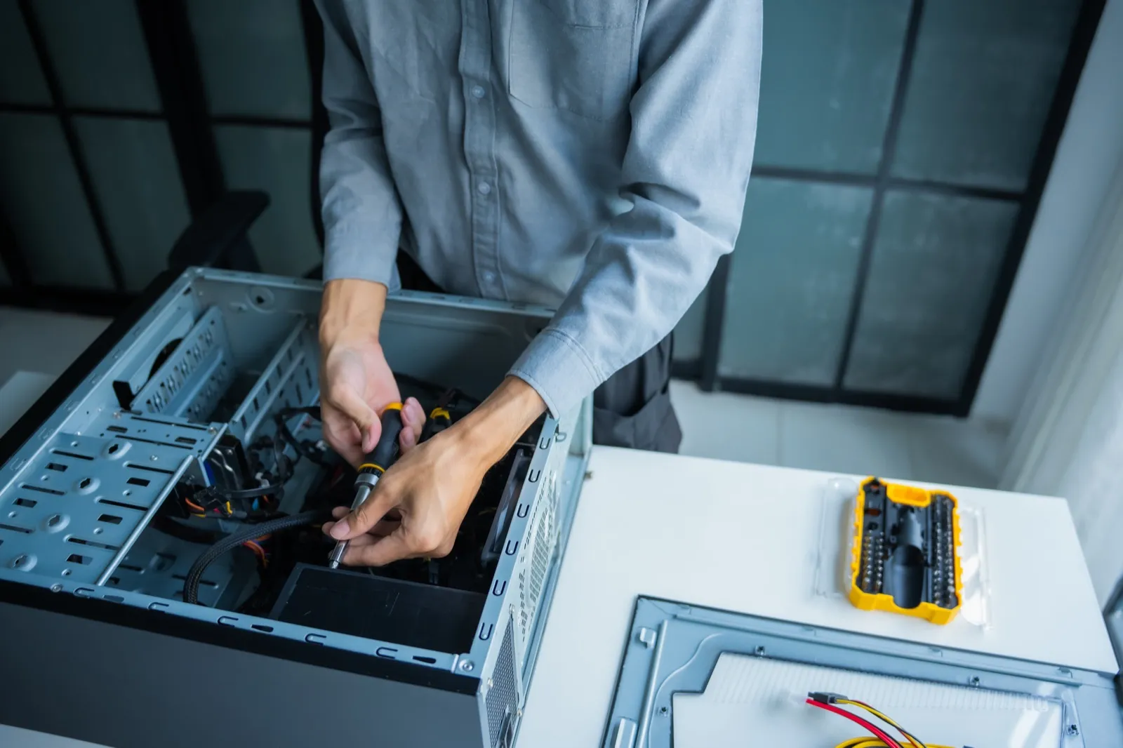 Technician repairing a desktop computer at a workbench