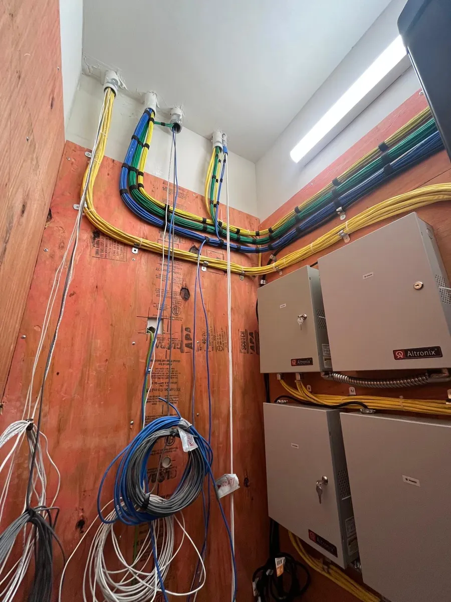 Conduit and cable runs entering access control panels on a plywood backboard