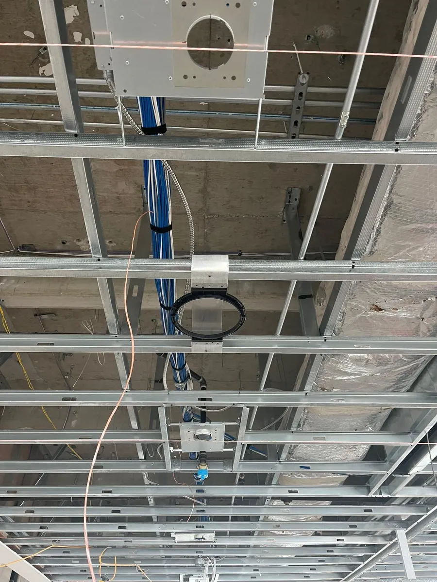 Open ceiling in a commercial buildout with cable rings routing network cable above the grid