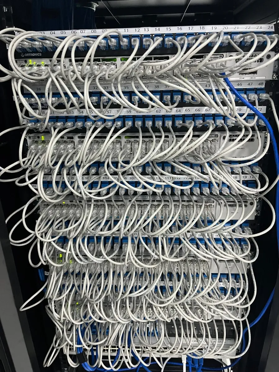 Stacked patch panels fully terminated with white patch cords, every port numbered